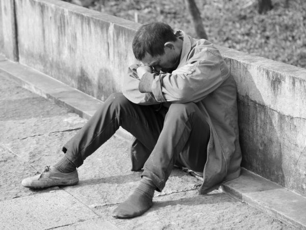 Kosten der Armut: Armer Mann sitzt deprimiert auf dem Gehweg
