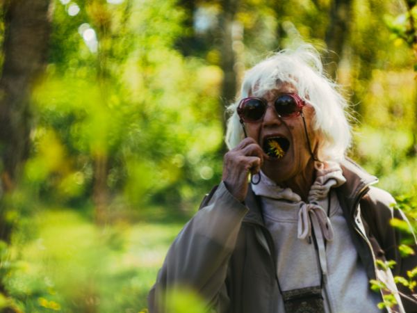 Das Rentensystem von Österreich: Ältere fröhlich wirkende Frau steckt sich eine Blume in den Mund