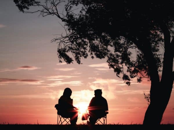 Ein älteres Ehepaar sitzt auf Campingstühlen im Sonnenuntergang.
